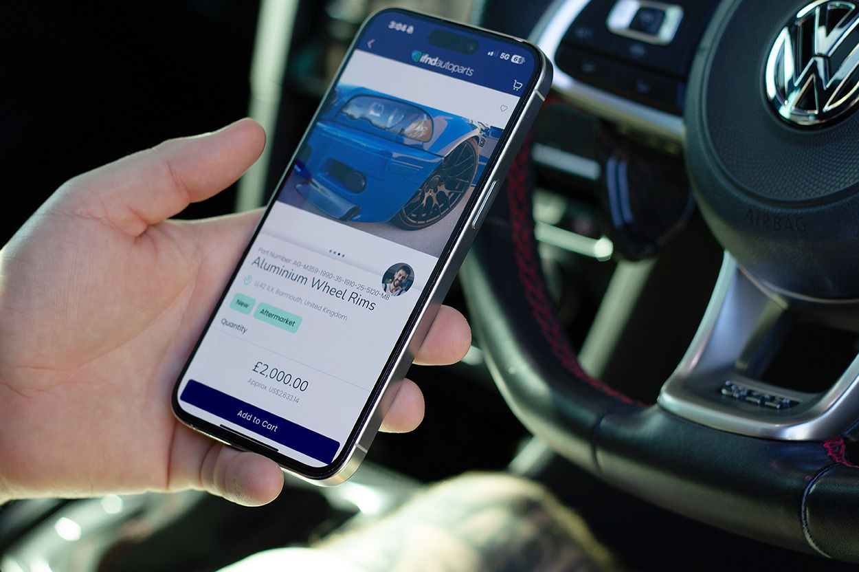 Man holding iPhone viewing a IFND Autoparts after searching for "the best place to sell my used cars in the UK"